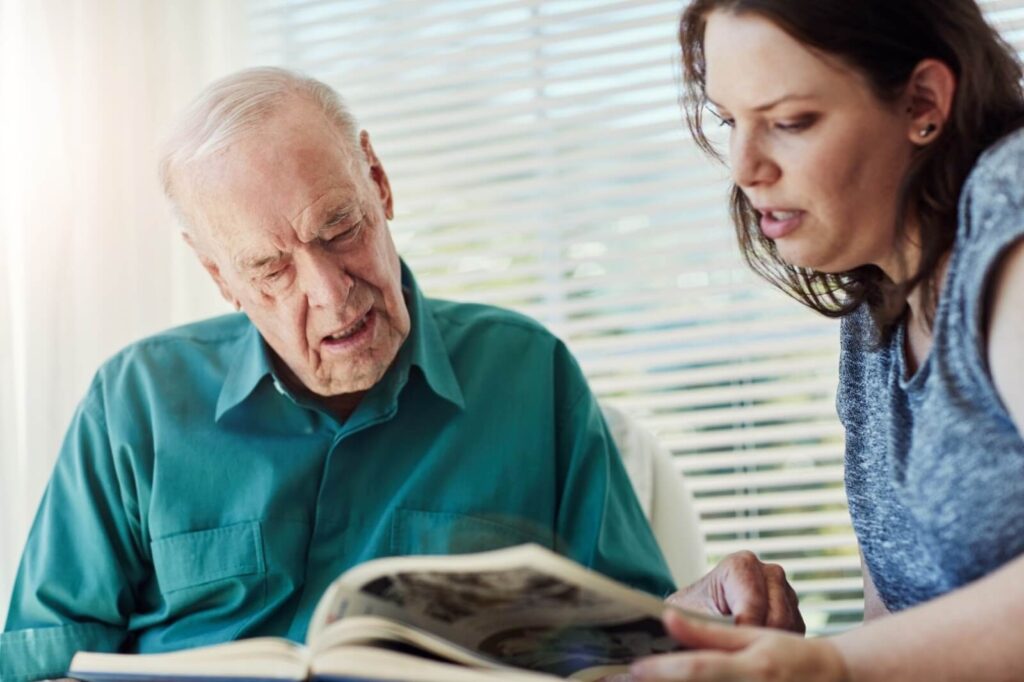 a senior reading a book with an adult carer